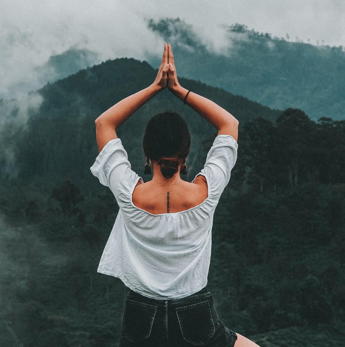a girl doing yoga with hills in the background