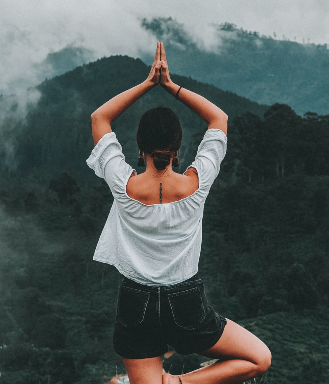 a girl doing yoga with hills in the background